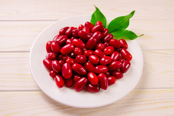 Cornela berries, on a white wooden background. Dogwood berries.