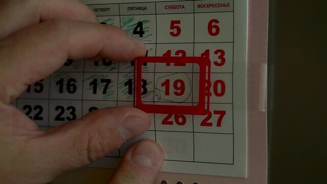 Human fingers move cursor to new date of wall calendar in early morning