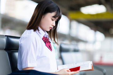 駅のベンチに座る女子高生