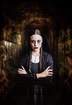A woman with long braids, with gothic and dark look, crosses her arms challenging, inside a corridor of dark and claustrophobic atmosphere, perfect for halloween