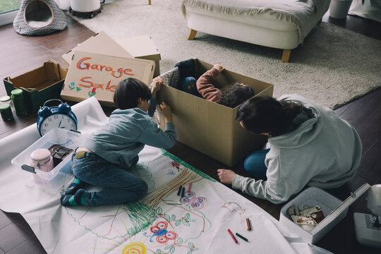 Mother with son drawing on cardboard box in living room at home