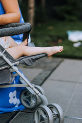 Feet of a barefoot little baby, a newborn baby sitting in a pram outdoors. Close-up photography, portrait, lifestyle.