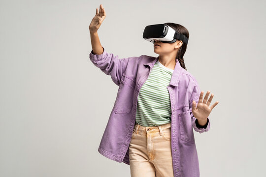 Teenage girl using virtual reality headset. Teenager testing vr grasses isolated on studio gray background. VR, future technology, gadgets, online gaming, training, exploring cyberspace, video game