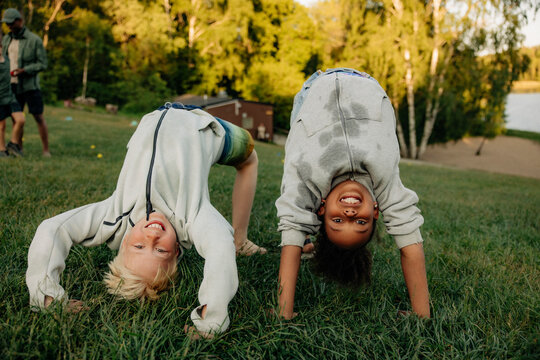 Portrait of playful male and female friends doing bridge position on grass in playground