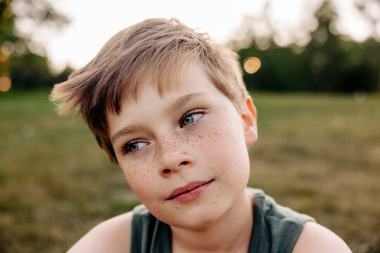 Boy with freckles day dreaming in playground