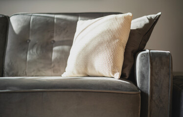 Gray velor sofa with cushions, shaded from the sun. Interior details and comfort. Abstract furniture background