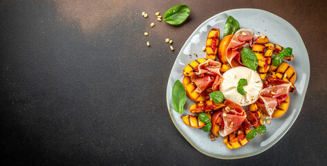 Grilled peach Caprese salad with mozzarella, prosciutto ham, basil and honey, for wine. Long banner...