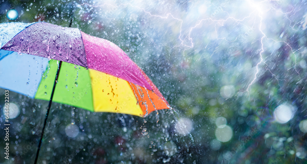 Wall mural rain on rainbow umbrella - weather concept - spring and fall shower with abstract defocused drops an