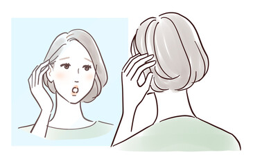 鏡を見ながら髪を触ってガッカリする中年女性