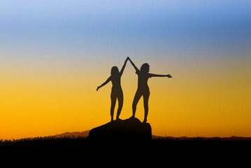 Silhouettes of Two Girls Embracing the Evening Sky