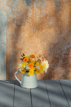 chrysanthemum flowers in jug on background old wall in sunlight