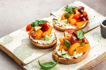Fototapeta na wymiar Gourmet sandwiches bread toast, bruschetta with cream cheese, peaches, tomatoes and green basil leaves