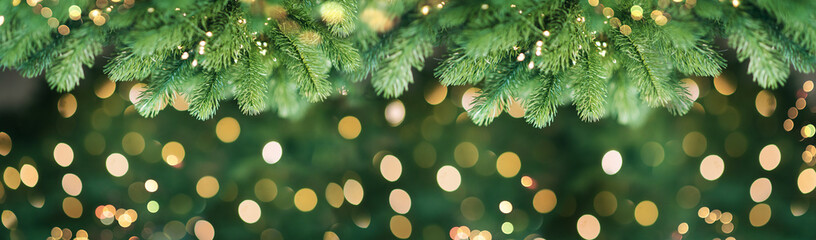 Merry christmas and new year holidays background. Blurred bokeh background with light bulbs and Christmas tree branches. Banner.