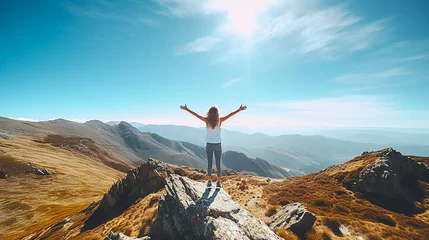 Fotobehang A woman feeling openness on a mountain peak with her arms outstretched. © Doraway