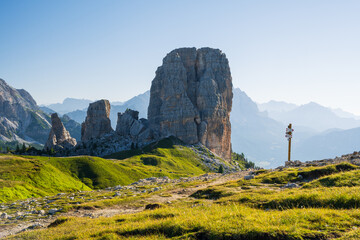 Cinque Torri peaks at summer cloudless morning with green grass lighteen by warm light of sun and...