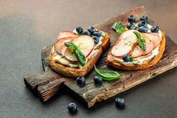 toast with cream cheese, honey, peaches and blueberries on a wooden board, place for text, top view