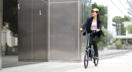 Eco friendly vehicle. 20s businesswoman ride bicycle to work in urban. Cycling has no pollution , alternate commute to global warming. Environmental preservation by riding bicycling. Commuting by bike