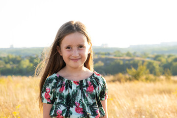 Portrait of a happy five-year-old girl in nature walking in the field in the summer.