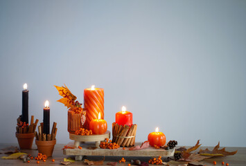 autumn decor with burning candles on wooden shelf on blue background