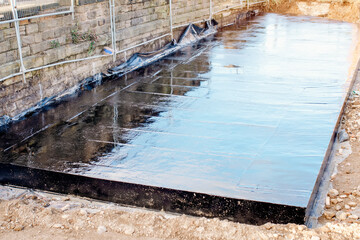 Waterproofing coating. Builder applying waterproofing bitumen mastic on concrete
