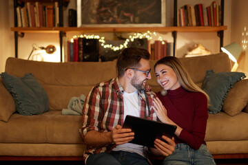 Young couple spending evening at home using digital tablet