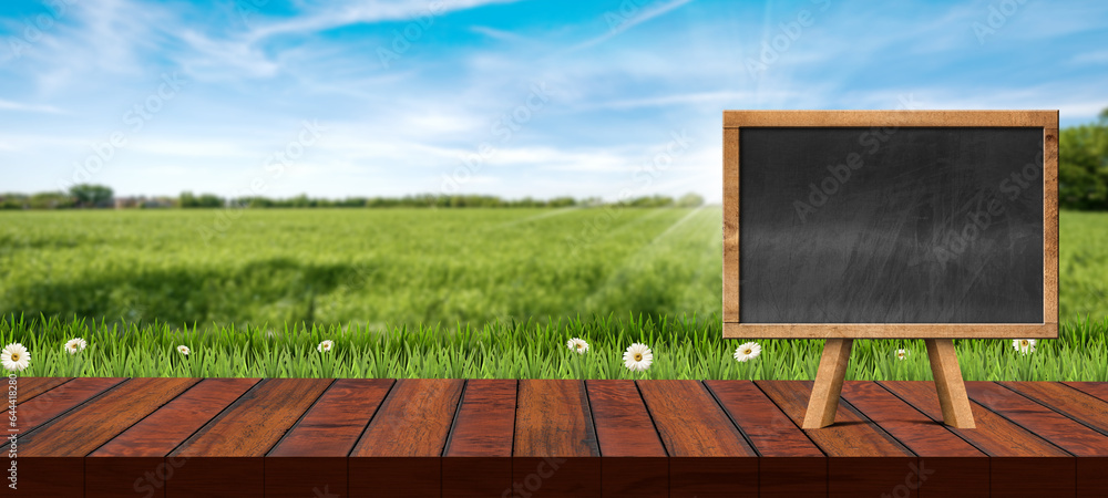 Poster close-up of an empty wooden table top for products display with blank small blackboard against a def