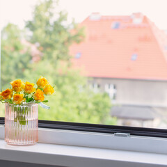 yellow roses in glass vase on windowsill