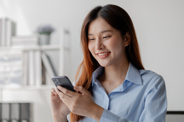 Asian woman holding smartphone, businesswoman using smartphone for social media and messaging with friends, using smartphone to send work email. Concepts of communication via the internet.