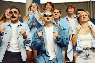 Concentrated people, men and women, sport fans watching live football match, game, cheering up...