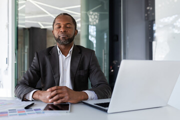 Balanced and calm man at workplace inside office, businessman meditating with closed eyes thinking...