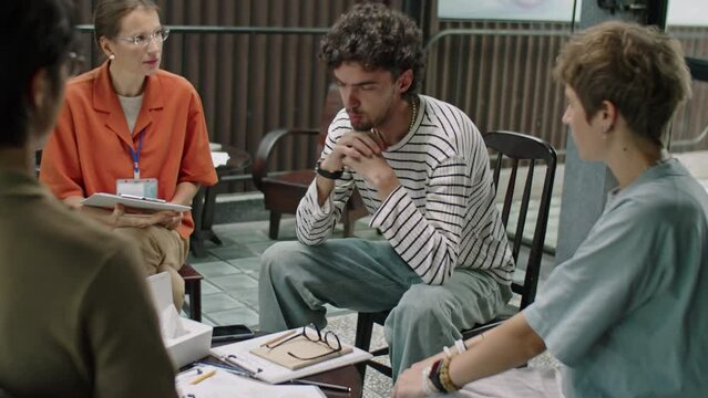 Stressed man discussing mental health problems with people and psychologist during group therapy session