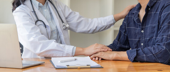 Female doctor giving encouragement to male patient by holding hand and a shoulder tap