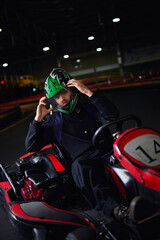 Fototapeta na wymiar racer taking off helmet and sitting in go kart after race on indoor circuit, adrenaline concept