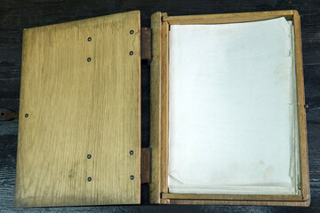 old log book in a wooden case with clasps on a black tabletop, open