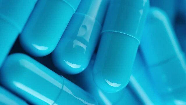 Heap of Blue pills capsule close up, rotation. Pharmaceutical Industry. The medicine concept. Vertical video