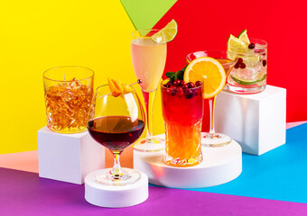 Summer cocktails in glasses with rum, gin, prosecco and liquors. Modern style still life on bright multi-colored geometric background