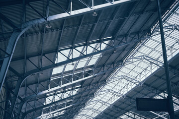 Metal arched frame construction. Steel roof supporting structures of railway station. Truss supports and glass translucent roof