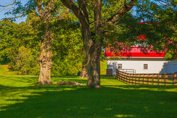 White barn with red roof in the trees