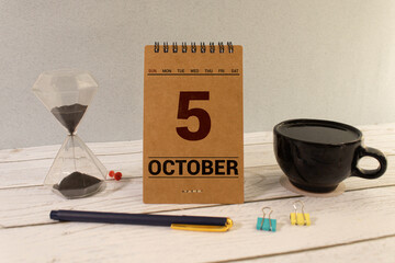 october 5. 5th day of month, calendar date. Stand for desktop calendar on beige wooden background.