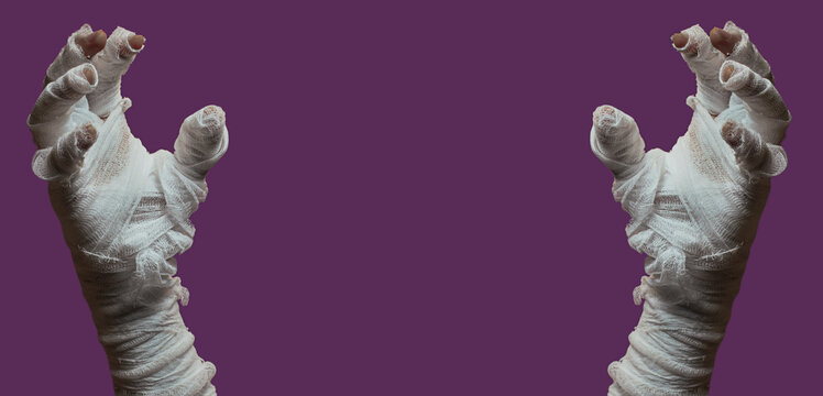 Halloween background. Bandaged hands of a zombie on a purple background. Halloween design.