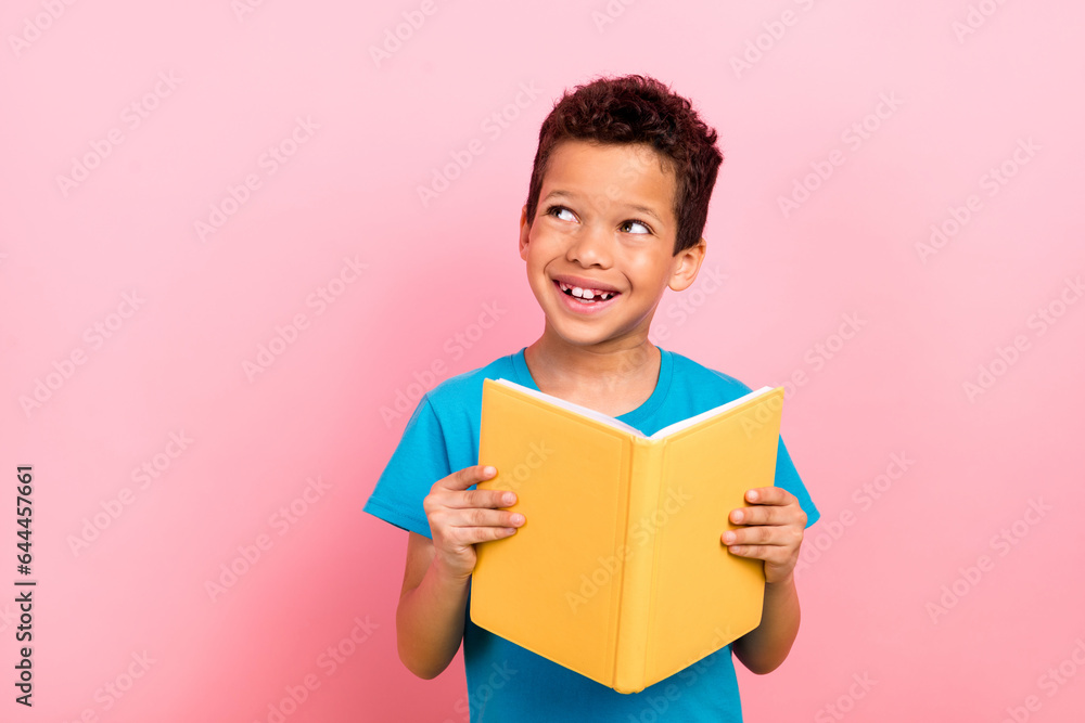 Wall mural Photo of dreamy thoughtful small boy wear blue t-shirt enjoying fairytales looking empty space isolated pink color background