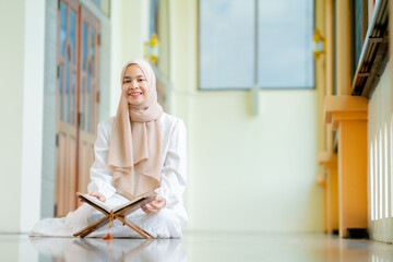 The image of an Asian Muslim woman in the Islamic religion in hijab in cream color. reading the...