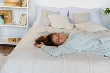 Sleeping student teenager lie on bed next to gadgets in the bedroom. Fatigue after study