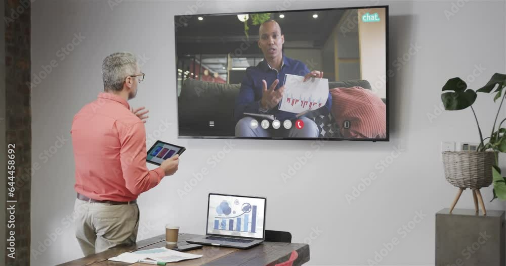 Wall mural Caucasian businessman on video call with african american male colleague on tv screen