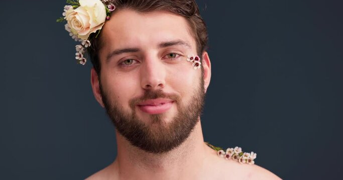 Flowers, self confidence and beauty with face of man in studio for acceptance, natural and pride. Skincare, plants and cosmetics with portrait of person on dark background for aesthetic and grooming