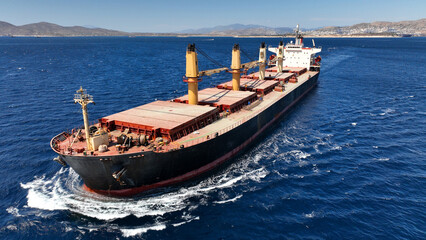 Aerial drone photo of bulk carrier ship carrying heavy merchandise and cruising deep blue open ocean sea