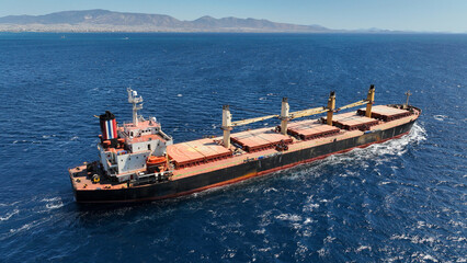 Aerial drone photo of bulk carrier ship carrying heavy merchandise and cruising deep blue open...