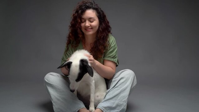 Woman and dog hug video footage. Lovely friends portrait looking at the camera. border collie pet cuddling with smiling curly haired owner woman in blue jeans. Vertical composition