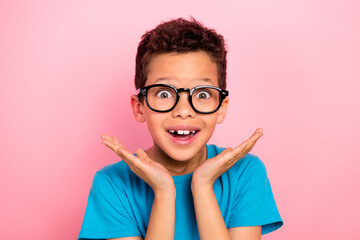 Photo portrait of charming small boy spectacles astonished raise hands dressed stylish blue garment isolated on pink color background