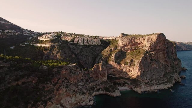 Aerial view of Breathtaking coastal panorama with clear blue sea, rugged cliffs, and the serene tranquility of small holiday houses,  Cala Moraig, Zona Encinas, Cumbre del Sol, Alicante, Spain